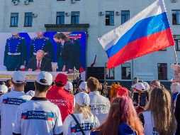 Habitantes ven una transmisión en vivo de la ceremonia para firmar tratados sobre la adhesión de nuevos territorios a Rusia en el centro de Luhansk, Ucrania. EFE