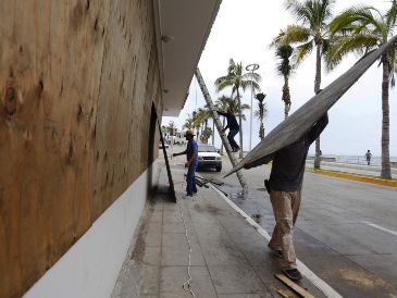 Trabajadores protegen ventanas en un edificio enfrente del mar ante la llegada de "Orlene" en Mazatlán, Sinaloa. AFP