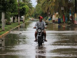 Un hombre pasea en una calle inundada tras el paso del ciclón 