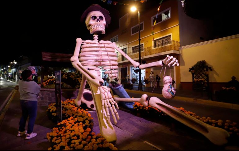 Visitantes observan una figura de calavera gigante en las calles del municipio de Atlixco, Puebla. EFE / H. Ríos