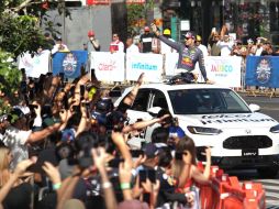 Niños, jóvenes y adultos mayores vestidos de pies a cabeza con el azul marino que caracteriza a la escudería del piloto tapatío intentan resguardarse de los rayos del sol, mientras el ánimo no desiste. EL INFORMADOR / A. Camacho