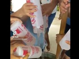 Los jóvenes vacían alcohol del 96 en un recipiente donde tienen una bebida. ESPECIAL