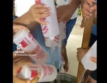 Los jóvenes vacían alcohol del 96 en un recipiente donde tienen una bebida. ESPECIAL