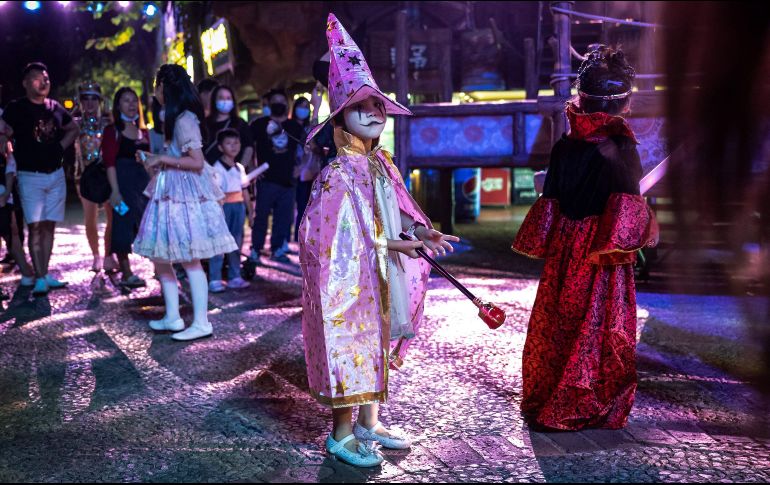 Personas disfrazadas caminan por las calle durante una celebración antes en Guangzhou, China. AFP