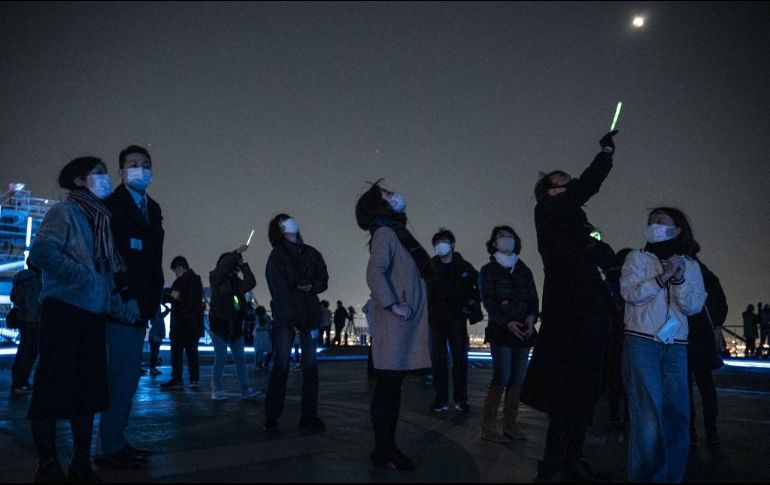 Miembros de los medios de comunicación y el público en general aprecian el fenómeno en el cielo de Tokio, Japón, en el techo de un edificio de gran altura. AFP / R. A. Brooks