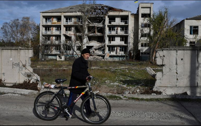 Un hombre con una bicicleta pasa frente a un edificio dañado por los bombardeos en la aldea liberada de Shchurove, región de Donetsk. AP/A. Andriyenko