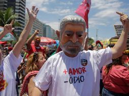 Un hombre con una mascara del presidente electo de Brasil, Luiz Inácio Lula da Silva, participa en una fiesta callejera llamada 