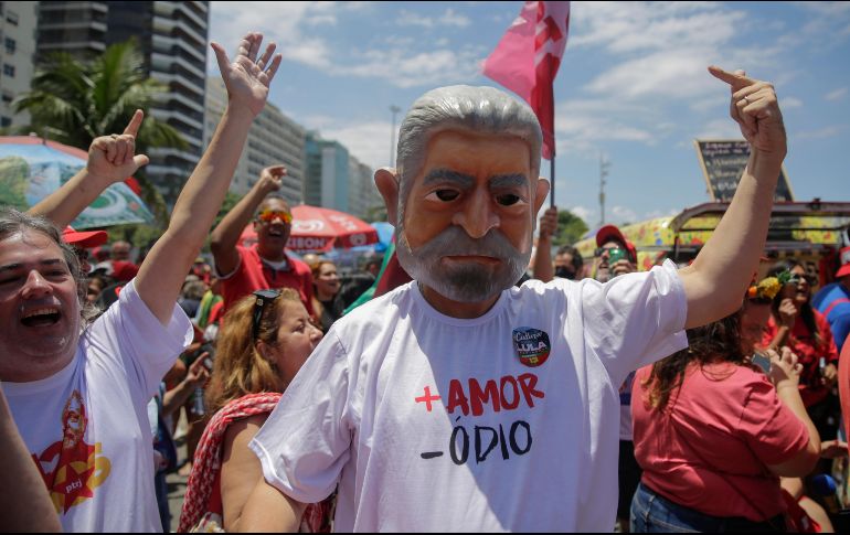 Un hombre con una mascara del presidente electo de Brasil, Luiz Inácio Lula da Silva, participa en una fiesta callejera llamada 