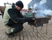 Un trabajador prueba el funcionamiento de estufas de metal hechas a mano destinadas a militares ucranianos y desplazados internos del este del país, en una fábrica en los suburbios de Lviv. EFE/M. Tys