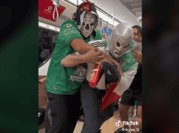 Entre empujones y gritos, con vasos en la mano, los personajes de la lucha libre mexicana chocan, mientras se escucha de fondo la tradicional canción 