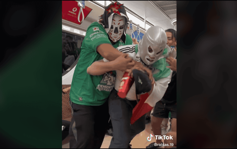 Entre empujones y gritos, con vasos en la mano, los personajes de la lucha libre mexicana chocan, mientras se escucha de fondo la tradicional canción 