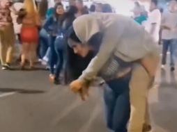 La mujer no se vio inmutada por las miradas de las personas alrededor, lo único que ella quería era llegar a su casa, aunque tuviera que cargar a su novio en la espalda. CAPTURA DE VIDEO