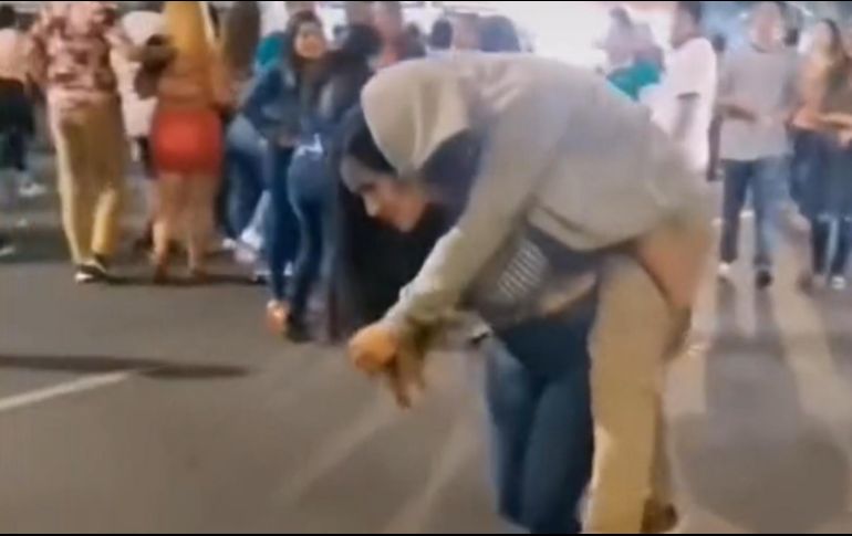 La mujer no se vio inmutada por las miradas de las personas alrededor, lo único que ella quería era llegar a su casa, aunque tuviera que cargar a su novio en la espalda. CAPTURA DE VIDEO