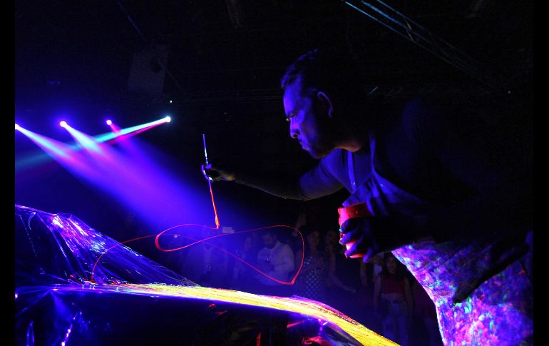 El artista intervino un automóvil de lujo enmarcada la actividad por una atmósfera en destellos neón que provenían de la obra expuesta y además con música de DJ de fondo. EL INFORMADOR / A. Camacho