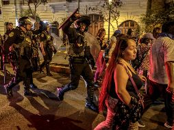 Policías caminan detrás de un grupo de personas durante una movilización antigubernamental en el centro histórico de Lima. EFE