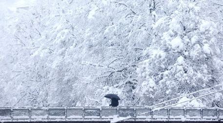 Un hombre que se protege con una sombrilla cruza un puente en medio de un nevado pasaje en Sarajevo, Bosnia. AP/A. Durgut