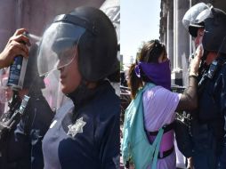 Si bien cayeron latas de aerosol, latas de refresco, agua, pintura blanca, roja, y carteles sobre las policías, estas se mantuvieron firmes, sin responder a los cuestionamientos de las mujeres. SUN / C. González