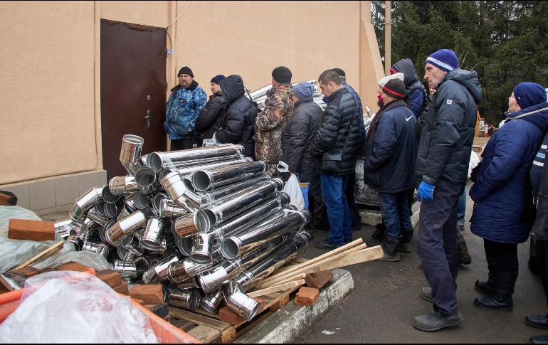 Lugareños reciben pequeñas estufas de leña en la aldea de Tsyrkuny, cerca de Kharkiv, Ucrania, por parte de voluntarios. EFE/S. Kozlov