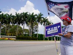 Más de 200 personas con carteles y banderas de Estados Unidos ovacionaron a Trump cuando pasó en un vehículo rumbo al aeropuerto. AP/E. Vucci