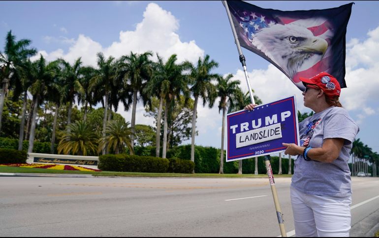 Más de 200 personas con carteles y banderas de Estados Unidos ovacionaron a Trump cuando pasó en un vehículo rumbo al aeropuerto. AP/E. Vucci