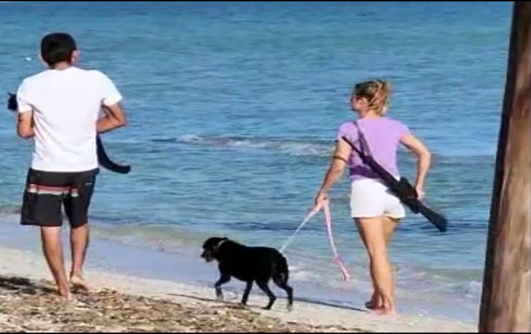 Imagen de la extranjera paseando en la playa con el arma. ESPECIAL