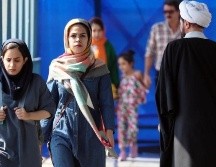 Mujeres iraníes caminan junto a un clérigo en una calle de Teherán en septiembre de 2022. EPA