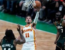 Trae Young esquiva la marca de Robert Williams III y Jaylen Brown. El guardia de Atlanta hizo 38 puntos anoche. AP/C. Krupa