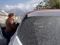 Una mujer aborda su auto cubierto de ceniza ante las continuas exhalaciones del volcán Popocatépetl, en la comunidad de San Pedro Benito Juárez, Puebla.  EFE / H. Ríos