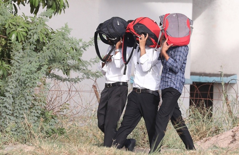 Estudiantes se cubren con sus mochilas de los intensos rayos del sol. EFE/H. Tyagi