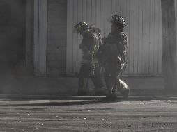 Los bomberos que acudieron a sofocar las llamas, y atribuyeron el siniestro al calentamiento excesivo de una computadora de mesa conectada a la energía eléctrica. SUN / ARCHIVO