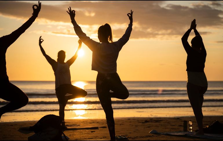 Miembros de la clase Happy Seal Yoga practican en Cayton Bay en Scarborough, Reino Unido, mientras sale el sol para celebrar el solsticio de verano. AP / D. Lawson