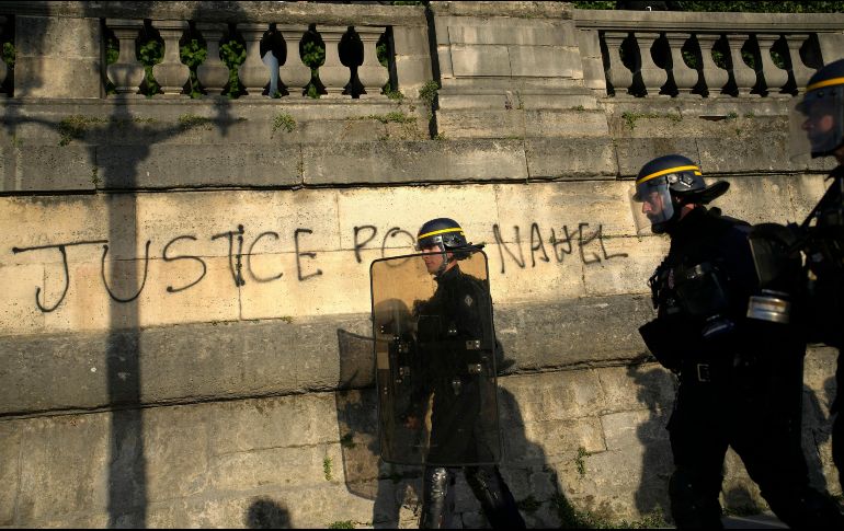 Policías patrullando junto a un grafitti con la leyenda 