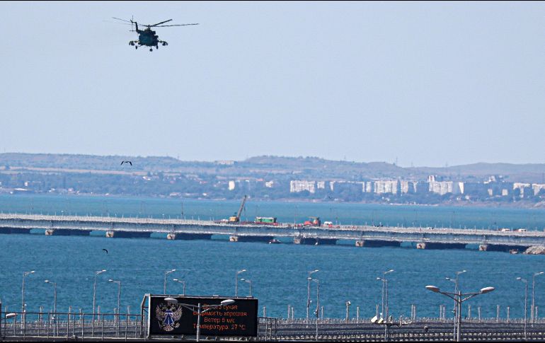 Un helicóptero militar ruso vuela sobre partes dañadas del puente que conecta a Rusia con la península de Crimea sobre el estrecho de Kerch. AP