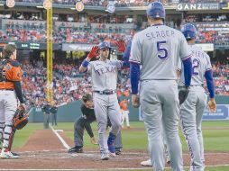 Adley Rutschman, izquierda, receptor de los Orioles de Baltimore, observa cómo Mitch Garver, centro, de los Rangers de Texas, celebra mientras cruza el plato. AP
