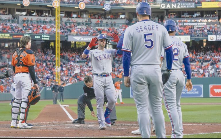 Adley Rutschman, izquierda, receptor de los Orioles de Baltimore, observa cómo Mitch Garver, centro, de los Rangers de Texas, celebra mientras cruza el plato. AP