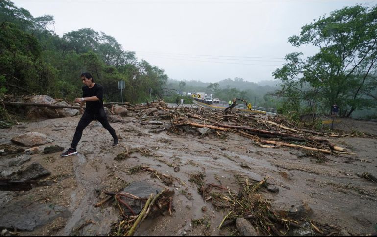 Un hombre cruza una carretera bloqueada por un deslizamiento de tierra provocado por el huracán 
