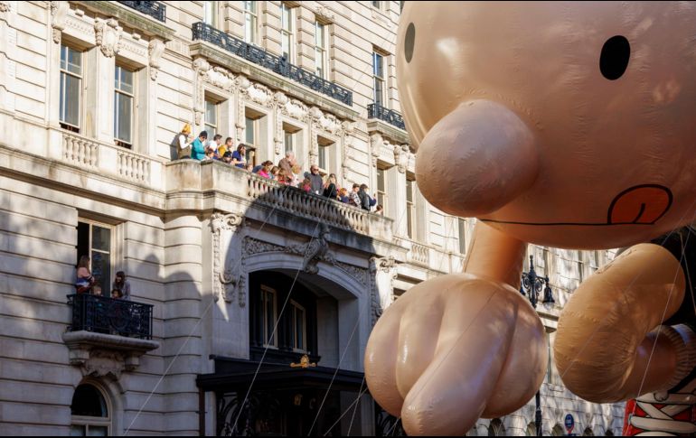 La gente observa el desfile del Día de Acción de Gracias desde un balcón mientras pasa el globo del 