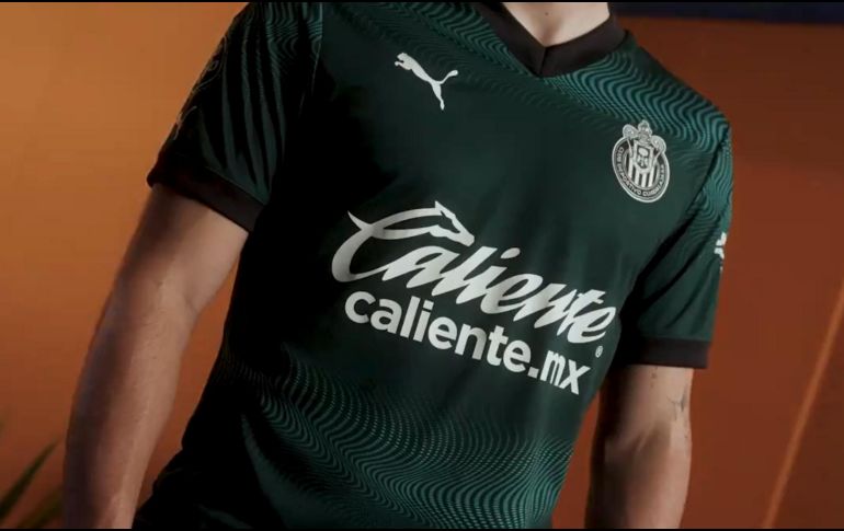 El color verde aparece en una tonalidad oscura que muestra detalles como líneas onduladas que atraviesan la prenda de forma horizontal. Así es el nuevo jersey de Chivas. ESPECIAL / Chivas