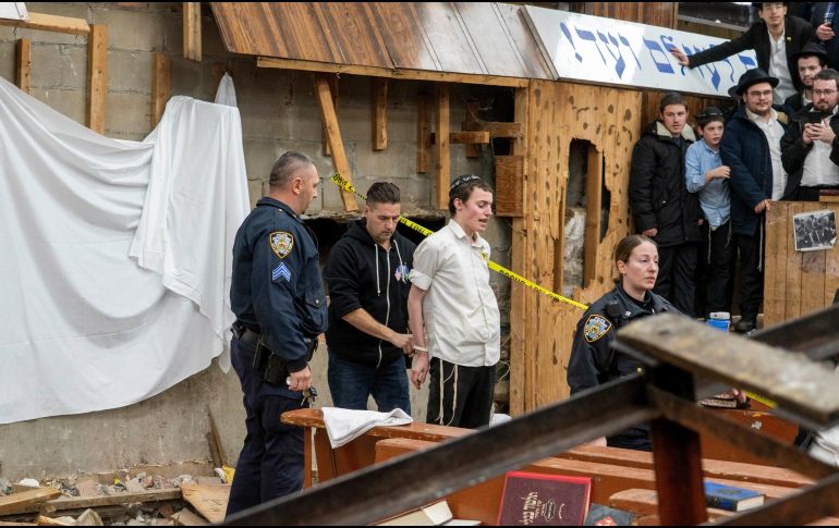 Agentes del Departamento de Policía de Nueva York arrestan a un estudiante judío jasídico luego de que fue sacado de una grieta en el muro de una sinagoga que conduce a un túnel excavado por estudiantes. AP / B. Schaff