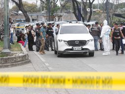 Policías investigan el vehículo con impactos de bala en el que se encontraba el fiscal. EFE