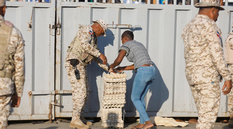 Un soldado ayuda a una mujer mientras cruza la frontera entre Quanamienthe en Haití y Dajabón en República Dominicana para trabajar en el mercado binacional. AFP