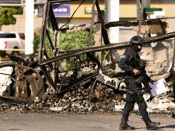 Un policía pasa junto a un vehículo quemado en octubre de 2019, en el llamado “Culiacanazo”. Hoy enfrentan otra crisis en el Estado. AFP