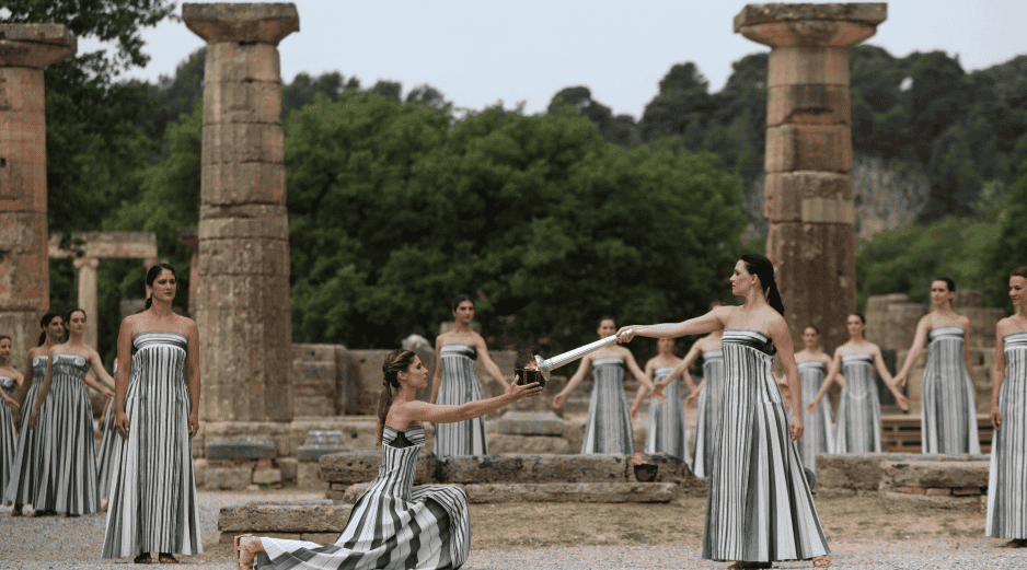 Una actriz vestida como una sacerdotisa griega utiliza el sol para prender una antorcha plateada tras ofrecer una oración simbólica a Apolo, el antiguo dios griego del Sol. EFE / G. Vitsaras