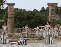 Una actriz vestida como una sacerdotisa griega utiliza el sol para prender una antorcha plateada tras ofrecer una oración simbólica a Apolo, el antiguo dios griego del Sol. EFE / G. Vitsaras