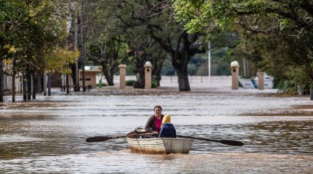 Una mujer acompañada de un niño conduce una embarcación por una calle inundada este lunes en Concordia (Argentina).  EFE/ Ignacio Jesús Rollano