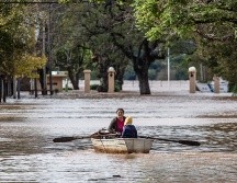 Una mujer acompañada de un niño conduce una embarcación por una calle inundada este lunes en Concordia (Argentina).  EFE/ Ignacio Jesús Rollano
