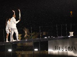 Los atletas galos Marie-Jose Perec (i) y Teddy Riner (d) caminan con la antorcha olímpica momentos antes de encender el pebetero. EFE/ Jan Woitas POOL