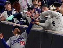 Fanáticos interfieren en un elevado de foul atrapado por el jardinero derecho Mookie Betts de los Dodgers de Los Ángeles. ARCHIVO / AP Foto