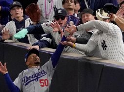 Fanáticos interfieren en un elevado de foul atrapado por el jardinero derecho Mookie Betts de los Dodgers de Los Ángeles. ARCHIVO / AP Foto