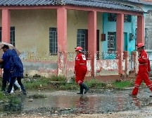 Integrantes de la Cruz Roja cubana caminan junto a unas personas durante una evacuación ante la llegada del huracán Rafael, este miércoles en Surgidero de Batabanó, un puerto pesquero en la provincia occidental de Mayabeque, a unos 50 kilómetros al sur de La Habana (Cuba). EFE/ E. Mastrascusa.